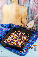 Beans mix in the jar and tray. Blue wooden table and background.