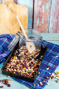 Beans mix in the jar and tray. Blue wooden table and background.