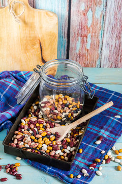 Beans mix in the jar and tray. Blue wooden table and background.