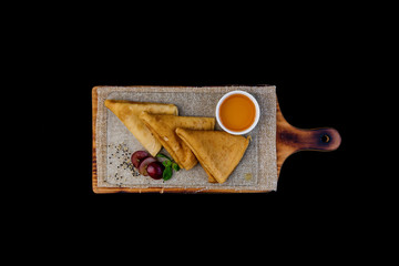 Thin pancakes or russian blini with honey leaf of mint and grapes. On a wooden board. Top view. Isolated on a black background