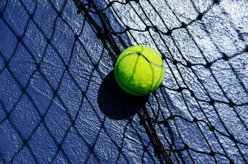 tennis ball leaning agaist the net court