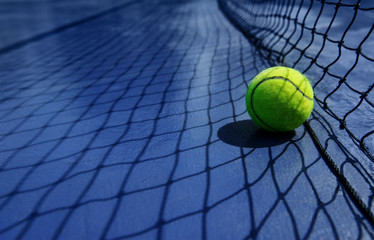 tennis ball leaning agaist the net court