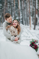 Bride and groom are hugging in the winter forest. Couple in love. Winter wedding ceremony.