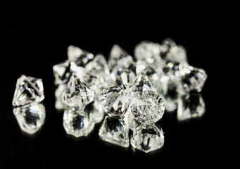 A bunch of shiny diamonds on a black mirror. Close-up shot.
