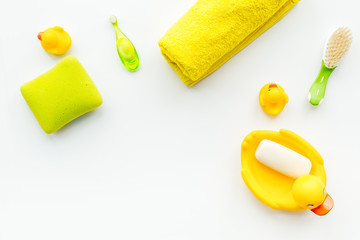 Baby bath set with yellow rubber duck. Soap, sponge, brushes, towel on white background top view copyspace