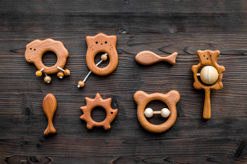 Cute wooden handmade toys for newborn on dark wooden background top view