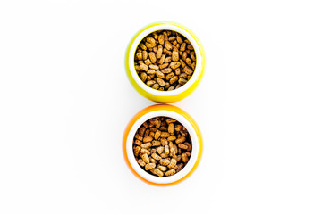 Dry pet food in bowls on white background top view copyspace