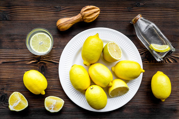 Fresh homemade lemonade. Lemons, juicer, glass for beverage on dark wooden background top view