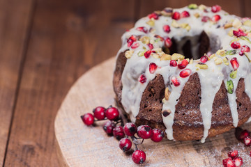 Close-up shot of a marble cake (gugelhupf) with vanilla orange glaze. Homemade, sugar free, wholegrain with pomegranate seeds and pistachio.