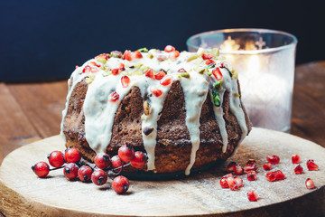 Close-up shot of a marble cake (gugelhupf) with vanilla orange glaze. Homemade, sugar free, wholegrain with pomegranate seeds and pistachio.