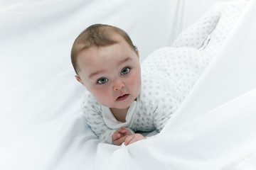 blue-eyed baby lying on the sheet