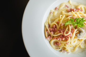 Creamy mushroom spaghetti in white dish over black table