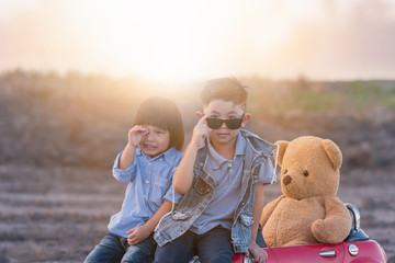 asian boy relaxation with teddy bear on big toy car.My son sit on road happy day