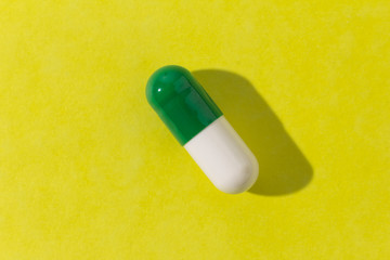 One white and green capsule on white background. Close up.