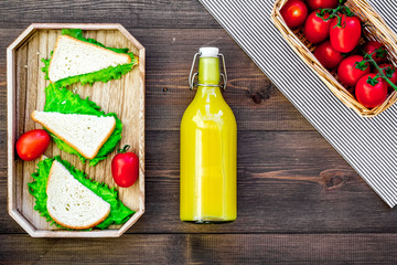 What bring for a picnic. Sanwiches, fruits, vegetables, juice on dark wooden background top view copyspace