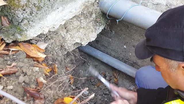 A worker man  makes a pit to empty old pipes for plumbing.