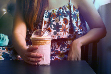 Women hold a cup of coffee frappe blending with ice, vintage concept.