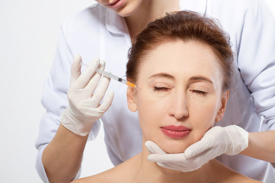 Plastic Surgery Concept. Doctor Hands Making Anti Aging Face Collagen Injection and Lifting Procedure Isolated on White Background. Copy Space and Mock Up. Macro Woman Face.