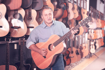 Male is playing on wooden acoustic guitar