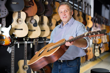 Male musician buying new acoustic guitar