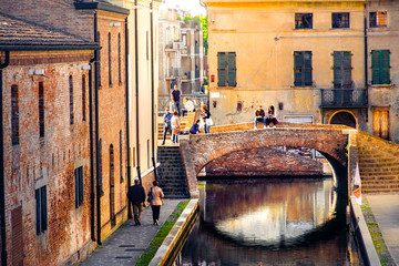 romantic getaways in italy,  warm tone lights at sunset over red bricks old buildings and bridge on the canal of Comacchio, Ferrara province, Emilia Romagna,  Italy