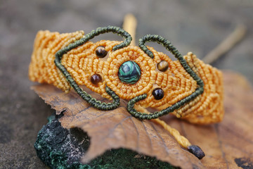 Obraz premium Macrame material handmade bracelet on natural background