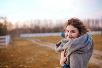 Smiling fashion woman walking in autumn park with warming scarf.