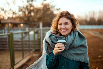 Happy woman warming up with hot coffee in cold autumn.