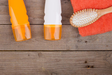 Set of bathing accessories - orange towel, hairbrush and cosmetics for pampering on brown wooden...