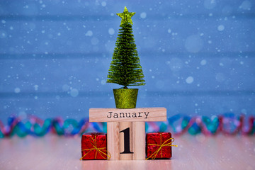 January 1st. Day 1 of January set on wooden calendar on blue wooden plank background. Winter time. New year background with snow. Christmas Holiday Composition
