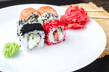 on the plate is white, lined with different rolls, sushi