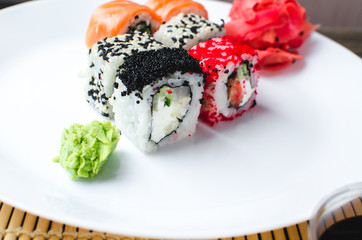 on the plate is white, lined with different rolls, sushi