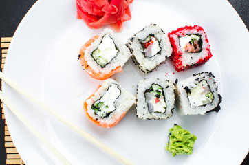 on the plate is white, lined with different rolls, sushi