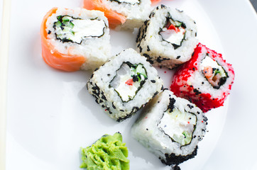 on the plate is white, lined with different rolls, sushi