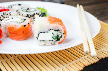 on the plate is white, lined with different rolls, sushi
