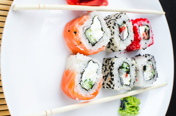 on the plate is white, lined with different rolls, sushi