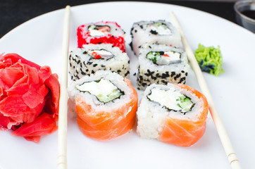 on the plate is white, lined with different rolls, sushi