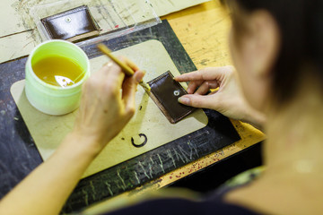 woman smearing with glue a part of a wallet