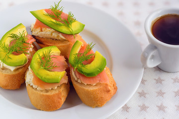 Bruschetta, snack sandwiches with white cheese, smoked salmon and pieces of avocado decorated by dill.