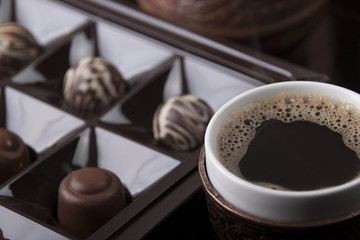 A cup of hot coffee and chocolate sweets