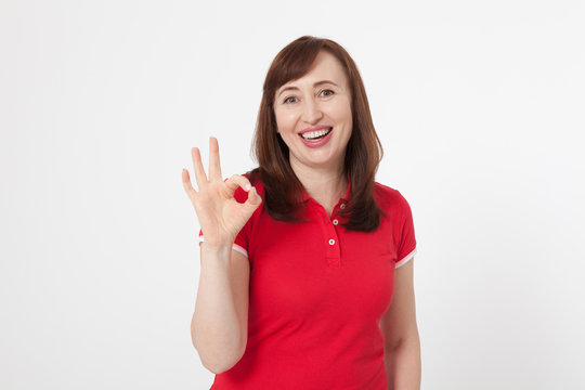 Smiling attractive middle aged woman showing thumbs up, okay. Isolated. Copy space