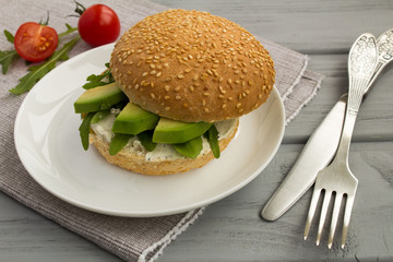 Vegetarian sandwich with avocado and arugula on the grey napkin