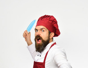 Cook with wild face in burgundy apron and chef hat.