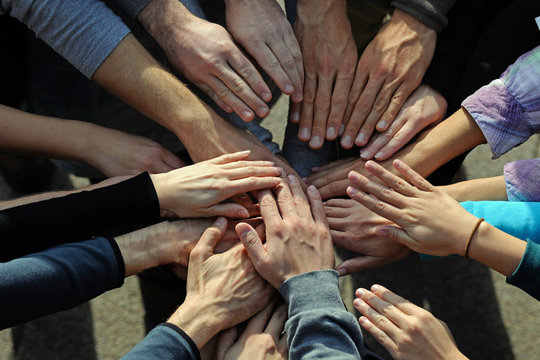 lots of hands come together in a circle