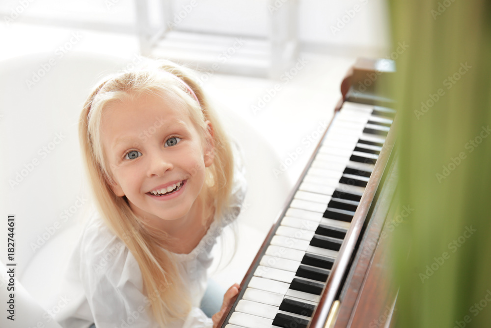 Poster Adorable little girl near piano indoors