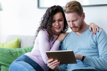 Obraz na płótnie Canvas Young couple using digital tablet at home