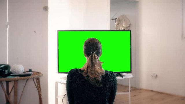 Girl Watching TV Alone at Home, Green Screen Background. Girl watching green screen television at home. Green screen footage for image replacement