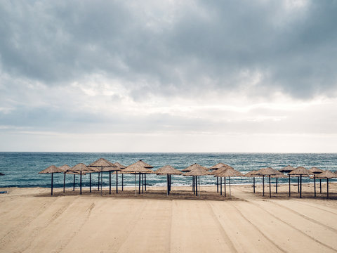 Aufgereihte Sonnenschirme an menschenleerem Strand
