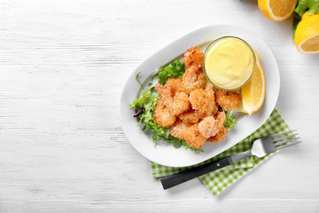 Plate with tasty shrimp basket and sauce on table