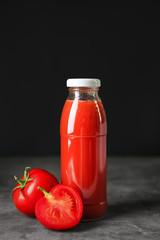 Bottle of tomato juice on table against black background